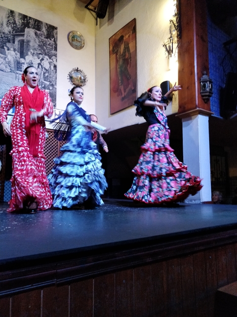       Dancers in colorful flamenco dresses performing on a stage.
  