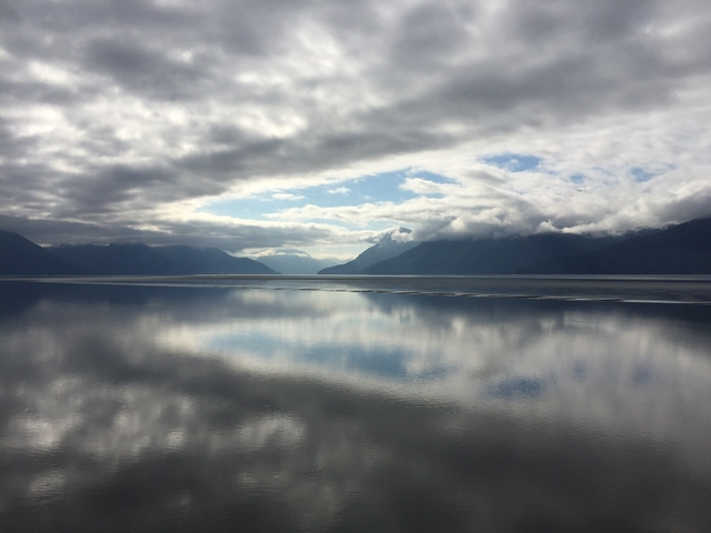       Serene view of a fjord with mountains and reflection in the water.
  
