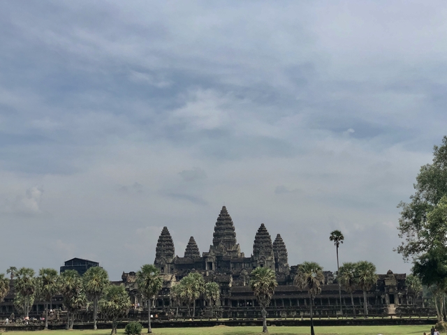       Distant view of Angkor Wat temple under a cloudy sky.
  
