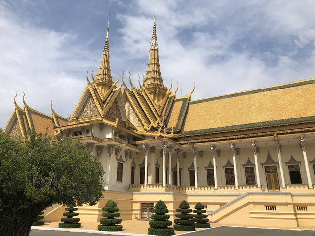       Ornate temple structure with golden spires against a cloudy sky.
  
