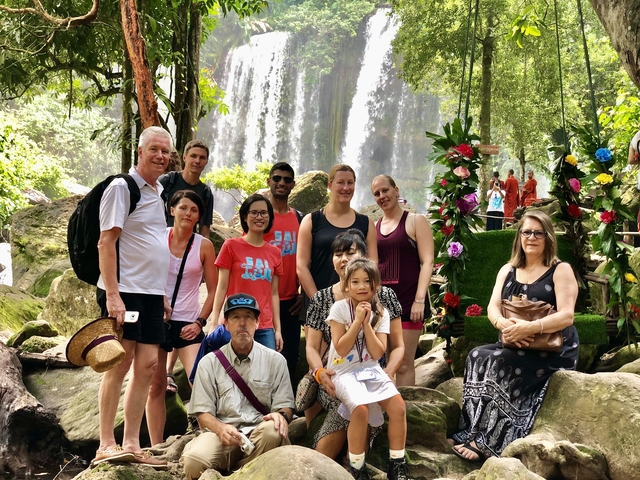       Group of people posing in front of a waterfall.
  