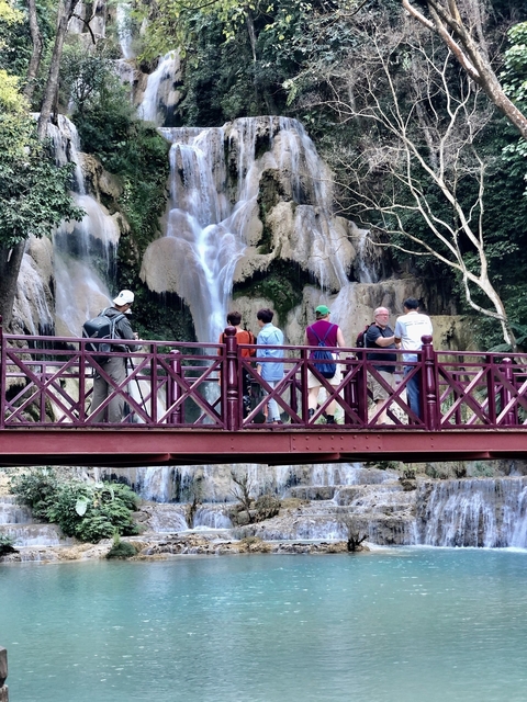 People on a bridge with a view of a waterfall in the background.
