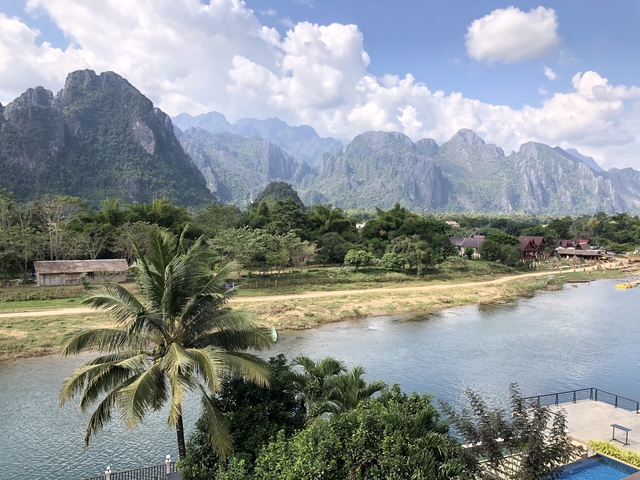       Breathtaking landscape of a river, palm trees, and towering peaks.
  