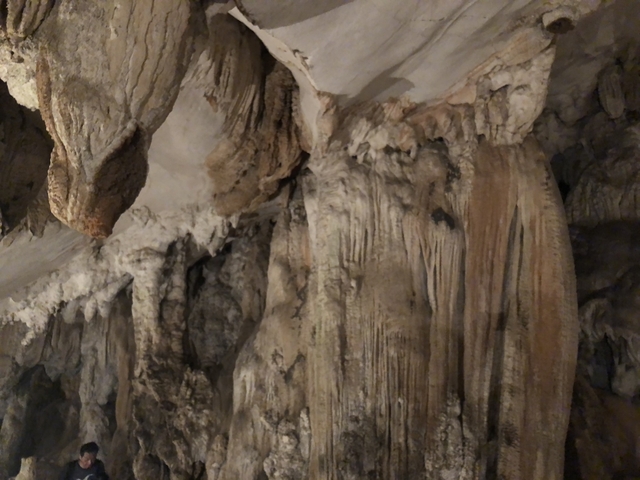 Inside of a cave with stalactites and rocky surfaces.
