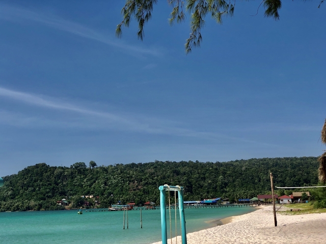       Coastal view with a beach and wooded hills.
  