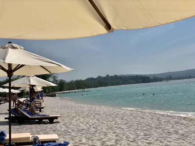 Beachside with lounge chairs under umbrellas.