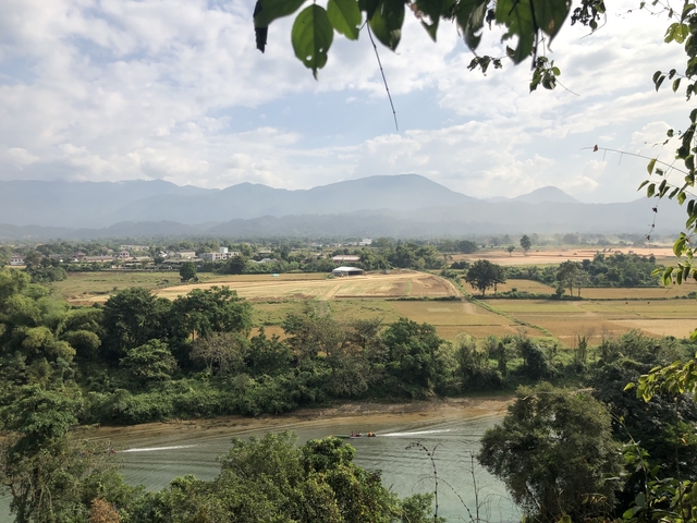 Pastoral landscape with fields and mountains under a clear sky.