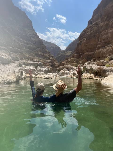 Person swimming in natural water amidst rocky surroundings.