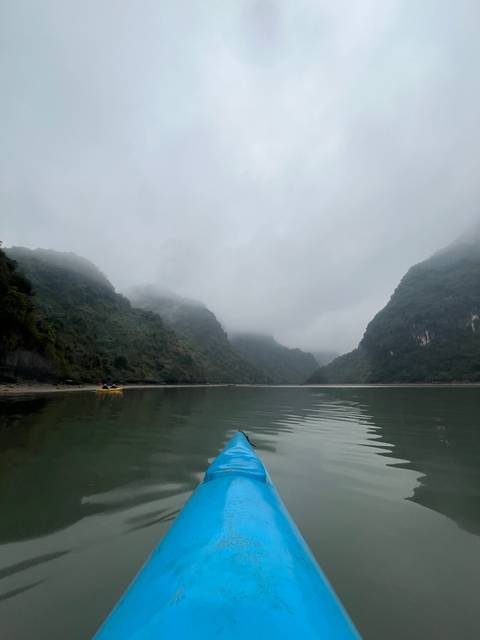       Misty mountains with a waterway, partially shown boat.
  