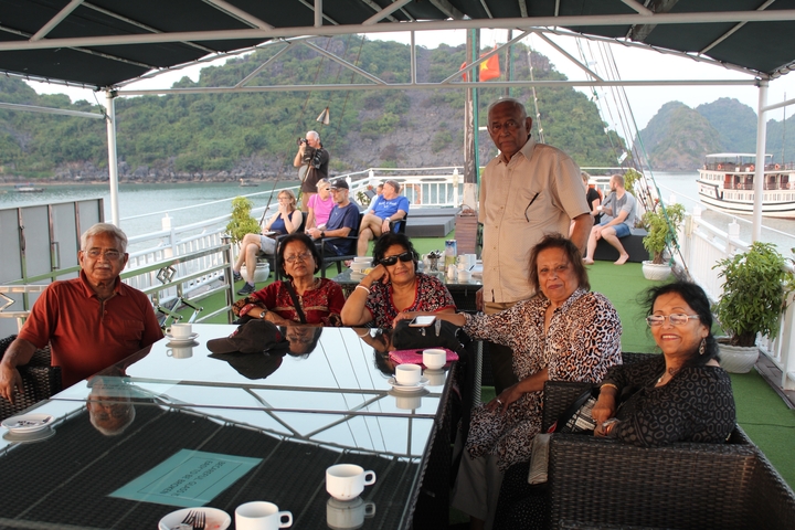 Group of people sitting on a boat, with hills and water in the background.