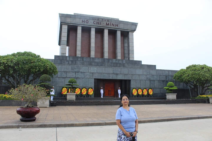 Person standing in front of a significant building with the name 'Ho Chi Minh' inscribed.