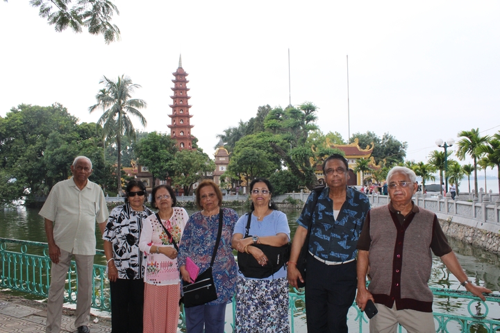 Group of people posing in front of the Tran Quoc Pagoda and a lake.
