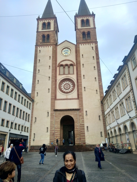       Tall clock tower with decorative features surrounded by buildings.
  
