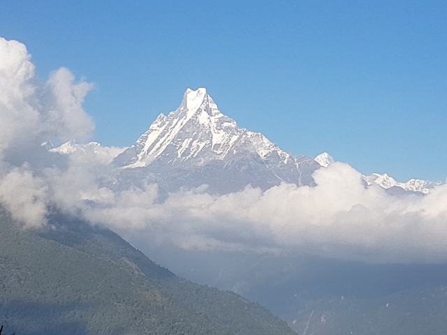 Sharp, snow-covered mountain peak above the clouds.