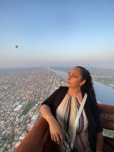       Person in a hot air balloon with cityscape below.
  