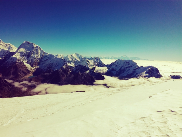 Expansive snow-covered mountain range under a clear blue sky.