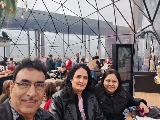 Group of people inside a glass cafe or viewpoint.