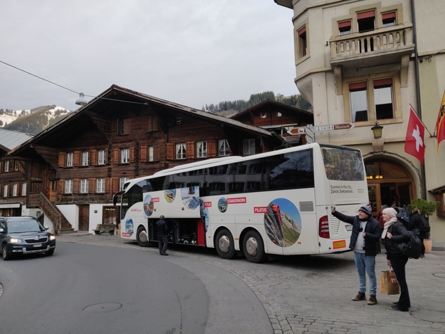 Tour bus parked in a village with traditional Swiss chalets.