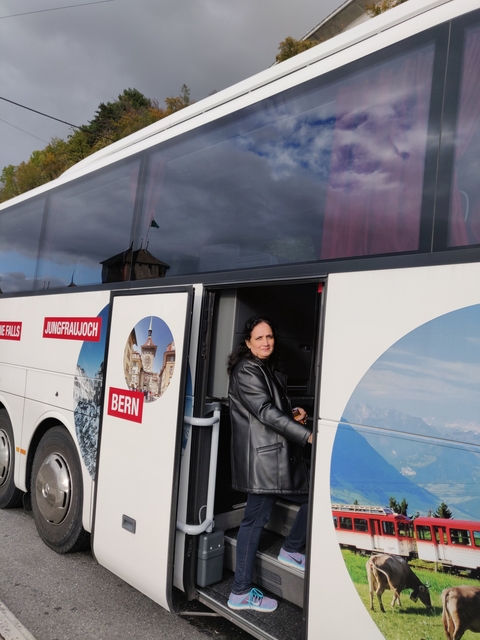 Person stepping out of a tourist bus with labels of Swiss destinations.