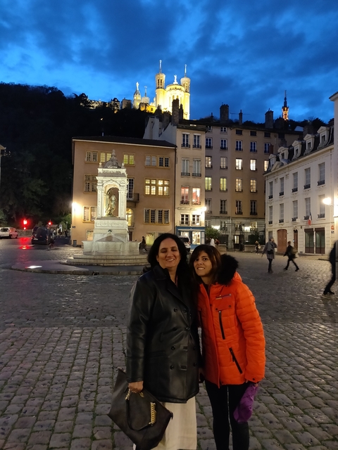 Two people posing in a cobblestone square at night.