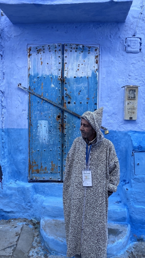       Portrait of a man in traditional clothing in front of a vivid blue door.
  