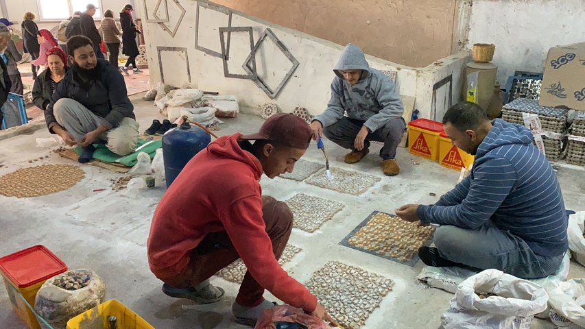       People working on traditional crafts with mosaic tiles.
  