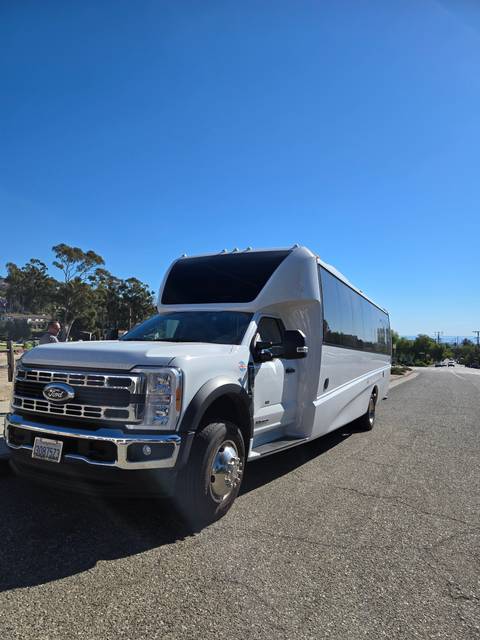 White tour bus parked on a flat paved surface.