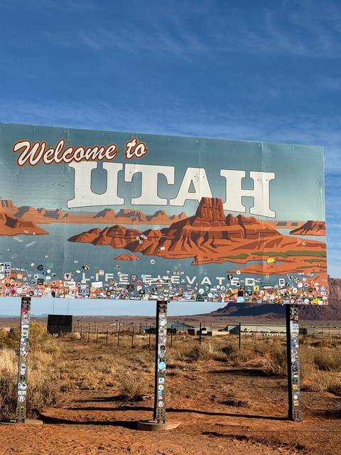 Welcome to Utah sign with stickers and symbols.