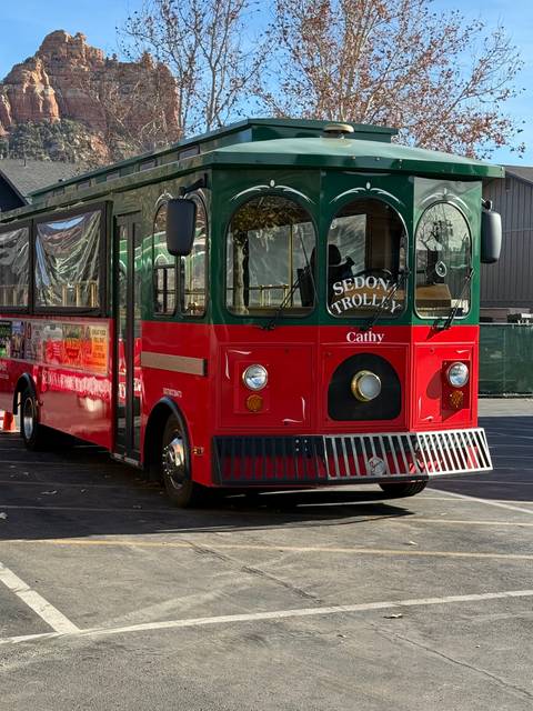 Red and green trolley bus parked on a street.