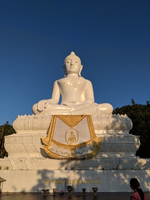 A large white Buddha statue in a detailed sculpture setting.