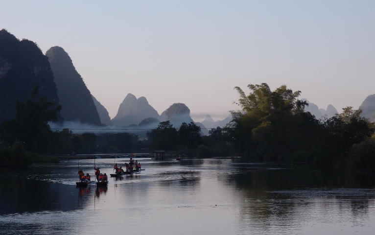 Bamboo boats on a calm river with karst hills.