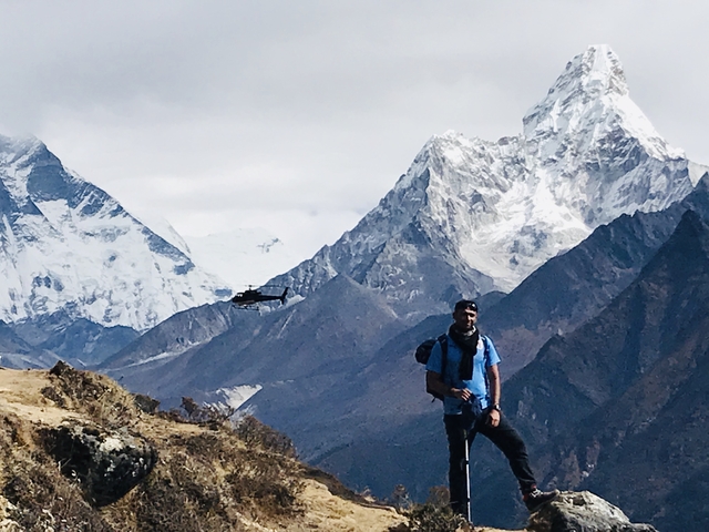       Person with trekking gear in the Himalayas with a helicopter.
  