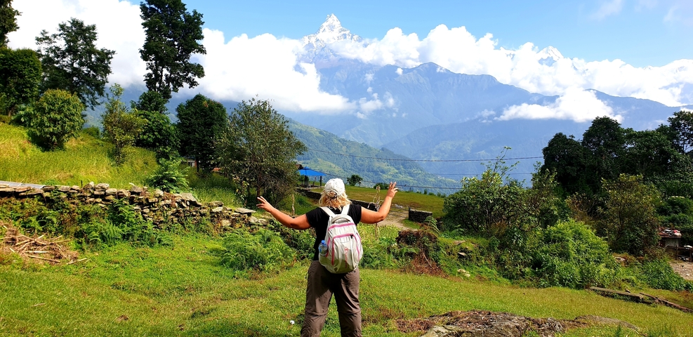 Person with arms raised in front of a breathtaking mountain view.