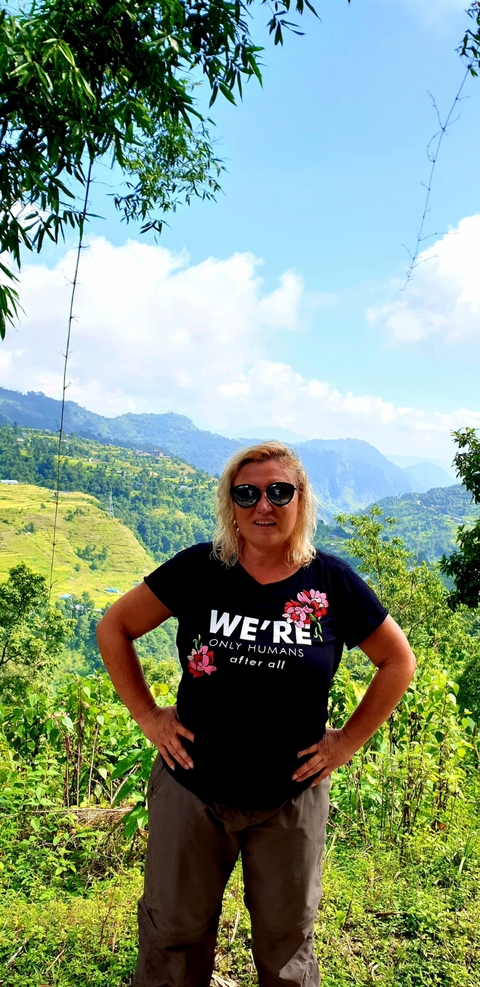 Person posing with a scenic hilly landscape.