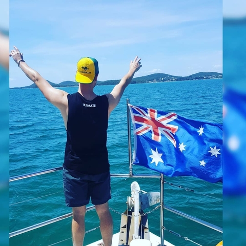 Person with arms outstretched on a boat with an Australian flag.