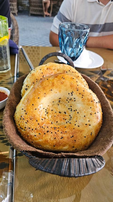       Basket of traditional bread with a glass of drink on a table.
  