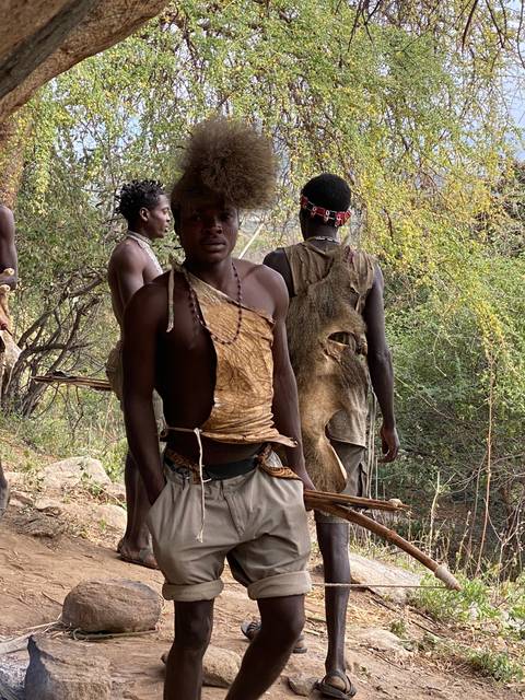       Group of tribal people walking through a natural setting.
  