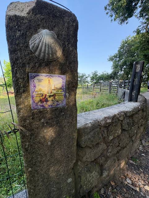 A stone marker with a shell and a sign indicating a pilgrimage route.