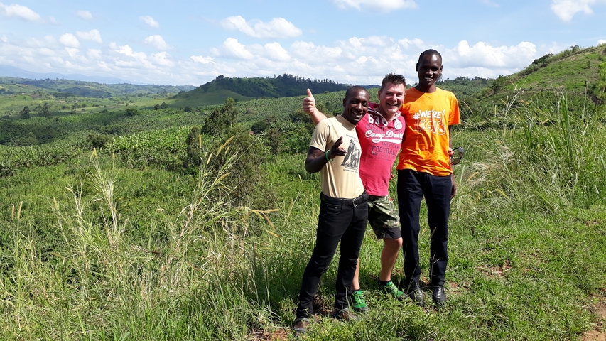 Group of people standing in a green, hilly landscape.