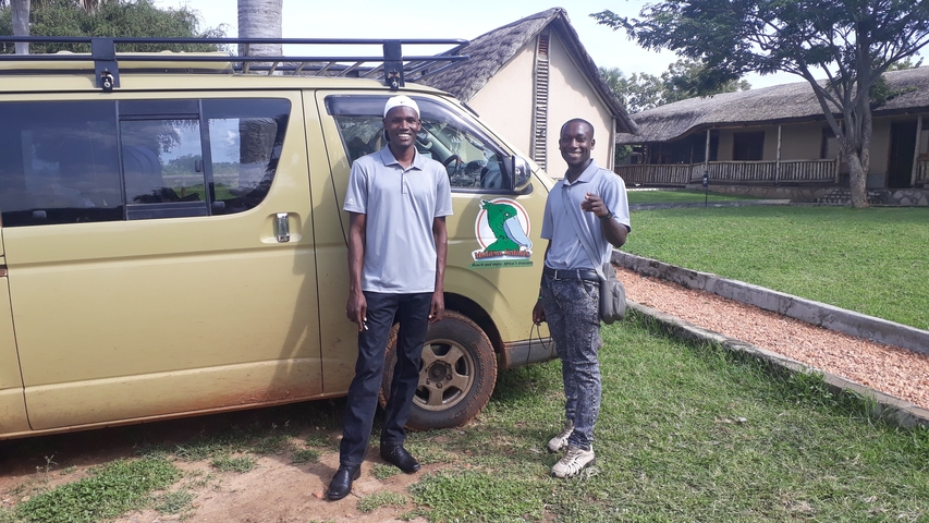 Two men standing beside a safari van.
