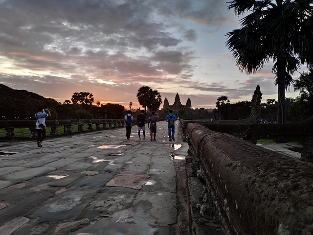       Group of people walking towards temples at sunset.
  