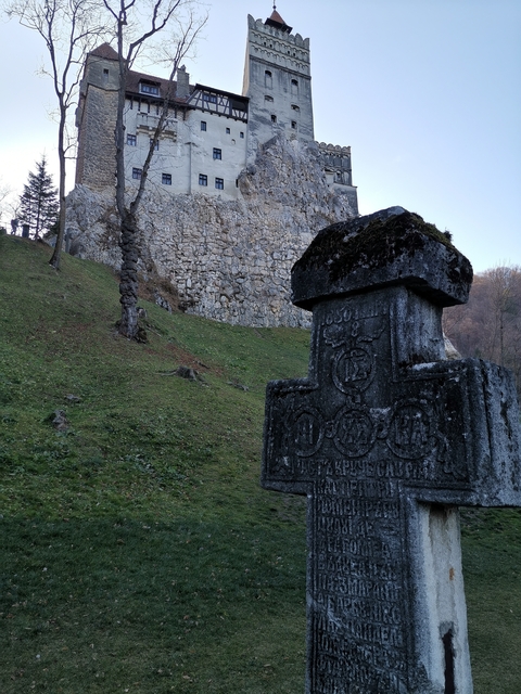       Stone cross in front of a hill or fortress wall.
  
