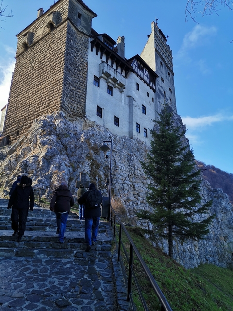 People approaching a fortress on a rocky hill.