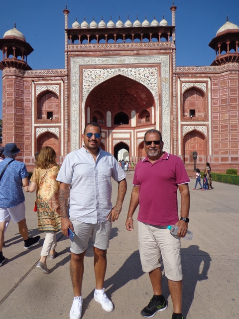       Two men posing in front of a grand entrance.
  