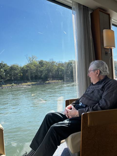 A person resting on a chair by a window.
