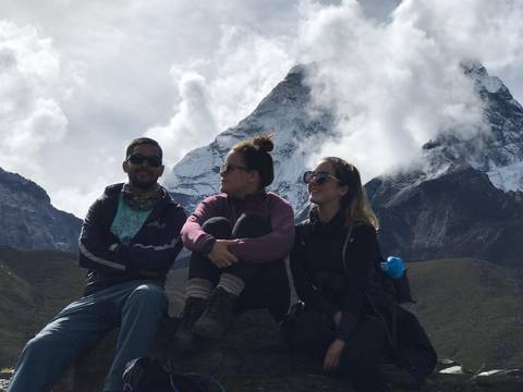Three people sitting with a mountainous backdrop.