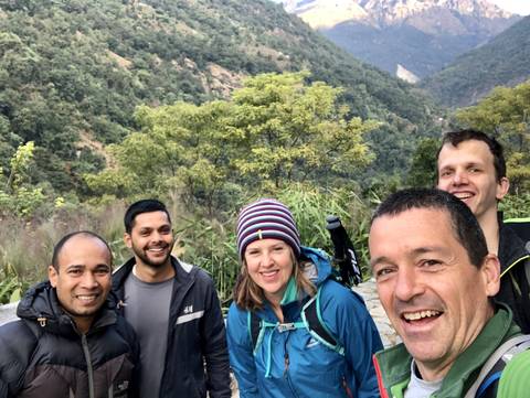 Group of people hiking in a mountainous area with lush greenery.