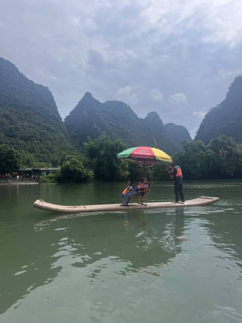 Two people enjoying a river ride under an umbrella.