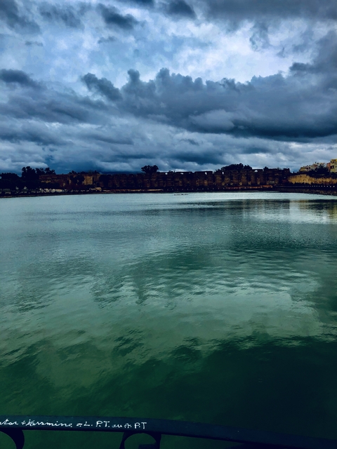 Calm lake with reflections under a cloudy sky.