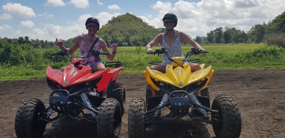 Two people on quad bikes in a scenic area.